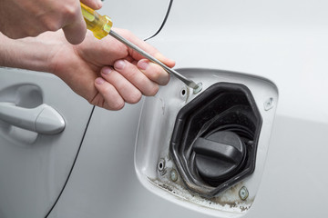 Employee hand repairing and change a white car fuel tank lid. Car repair problem and solution concept. 