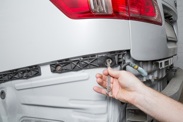 Employee hand repairing and change a white car back bumper. Car repair problem and solution...