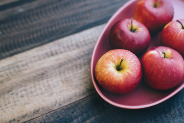 red apple in a plate on a wooden table.fruit