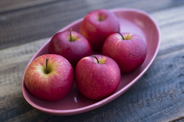 red apple in a plate on a wooden table.fruit