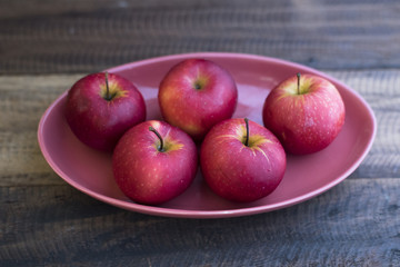 red apple in a plate on a wooden table.fruit