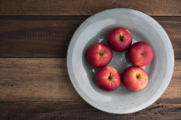 red apple in a plate on a wooden table.fruit