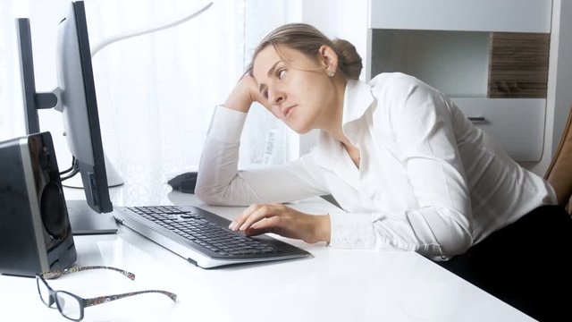 4k footage of young overworked businesswoman falling asleep at office while working on computer