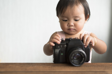 little asian toddler playing with old film camera (dslr). learning concept