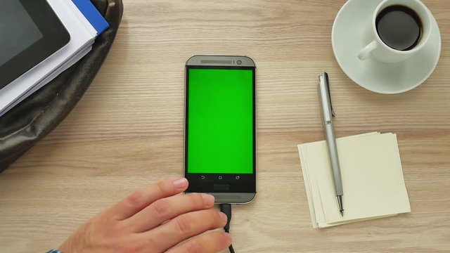 Man using a modern smartphone with green screen at her desk - green screen for placement of your own content