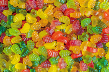 background of many bright and colored jelly sweets with free space for text, top view