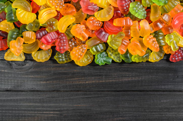 jelly and marmalade candies on a wooden background with free space for text.