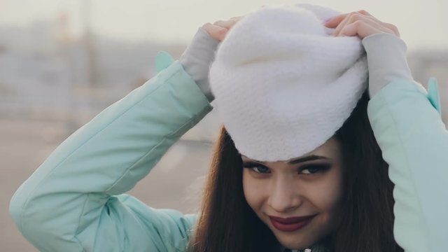 Joyful girl wearing white hat at winter outdoor