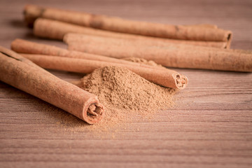 cinnamon sticks and powder on wooden table.