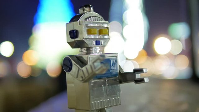 Toy the robot walking at the holiday night city center close-up macro 4k
