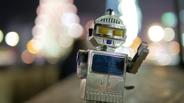 Soviet robot the toy walks around night city center with beautiful bokeh and blur background close-up 4k