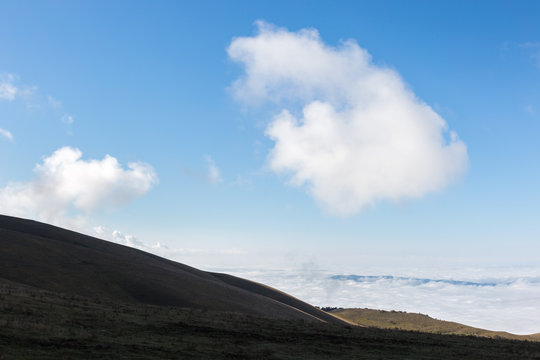 View of Subasio mountain (Umbria) over valley filled by fog, and beneath a wide sky with white clouds