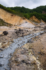 Fototapeta na wymiar Small river streams through the rocks of Hell Valley (Jigokudani), Noboribetsu, Hokkaido, Japan