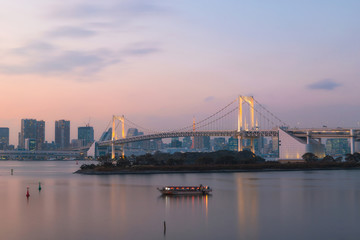 Tokyo Rainbow Bridge with Tokyo skyline at dusk.
