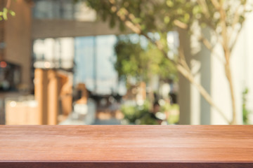 Wooden board empty table top on of blurred background. Perspective brown wood table over blur in coffee shop background - can be used mock up for montage products display or design key visual layout.