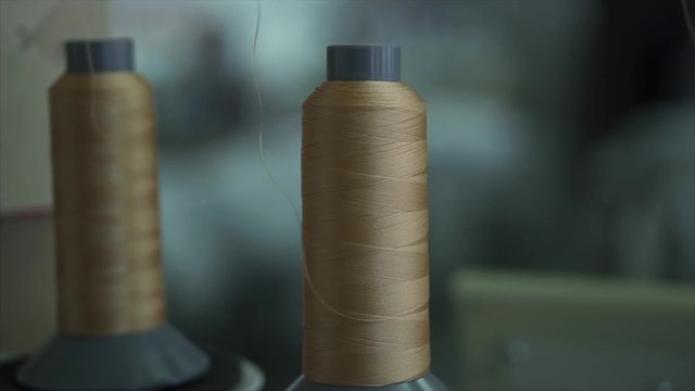 Rollers roll the fabric in the factory. Quality checking. A woman checks the cloth behind the machine. The machine with the rollers is working. Quality control. Female hands roll the fabric into roll