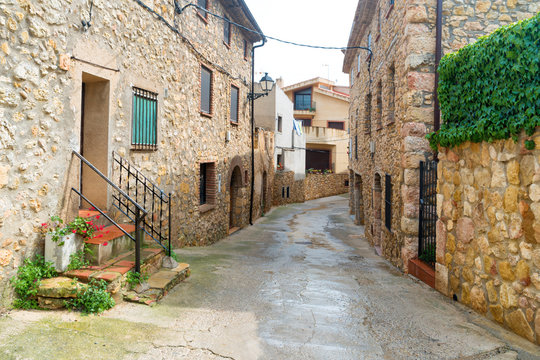 Fototapeta Old street in a european town with road and stone buildings