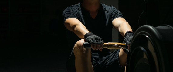 athlete in the dark is engaged in rowing on the simulator