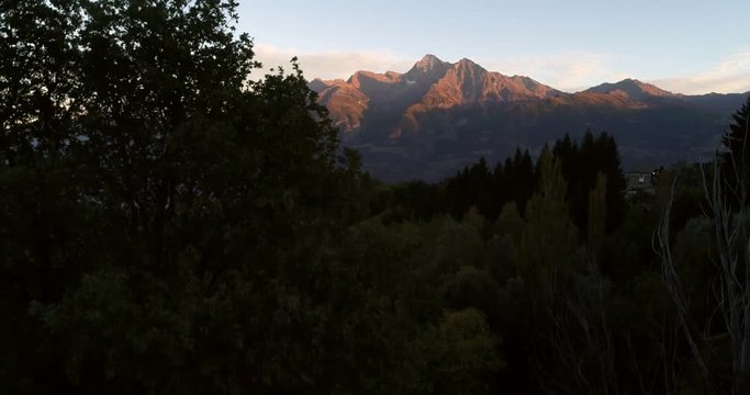 Alpine sunset, Cinema 4k rising view behind a grave cross, revealing mountains, on a sunny autumn evening dawn, near grand san bernardo pass, in Aosta, Italy