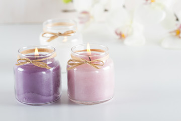 Fototapeta na wymiar Burning purple, pink and white candles on white table