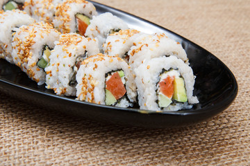 Uramaki sushi rolls with avocado and red fish on ceramic plate