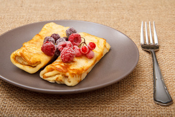 Homemade pancakes filled with cottage cheese and topped with frozen raspberries and blackberries on plate
