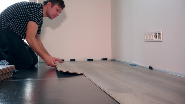settler man laying laminate flooring in new room at home.