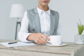cropped image of businesswoman taking cup isolated on gray