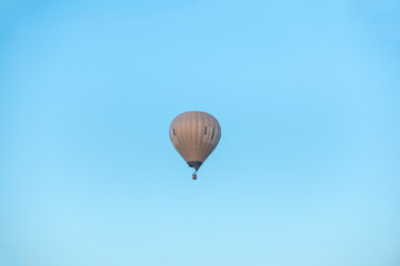Hot air balloon flying high in the air on clear blue sky background. 