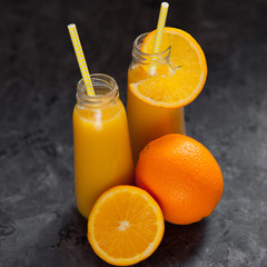 Fototapeta na wymiar Still life of two bottle full of orange juice and sliced fruits.