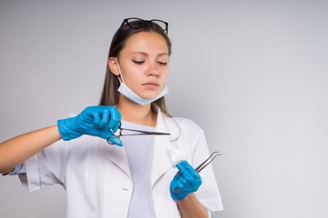 Serious medical woman holding cotton wool with tongs, preparing for manipulations
