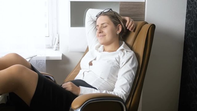 4k footage of young businesswoman relaxing and rocking in big office chair