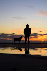 Fototapeta na wymiar Silhouette of man with his dog at sunset on background