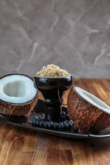 Shisha coconut in glossy black cup on a plate with opened coconut