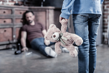 My toy. Selective focus of a fluffy bear being held by a nice sad depressed girl while looking at her father