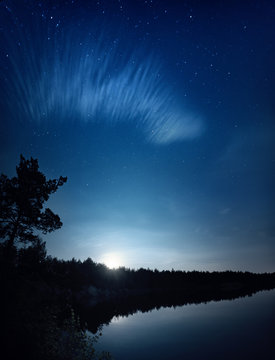 Lake at night with amazing starry sky, moon and clouds. Natural outddors travel dark background.