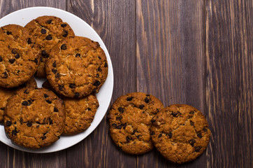 Homemade oatmeal cookies on a white plate. Wooden background. Space for text