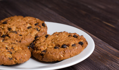 Homemade oatmeal cookies on a white plate. Wooden background.