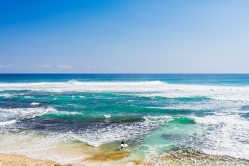 A single surfer stands at the short at the famous Margaret River beach, in the South West of Western Australia, Australia.