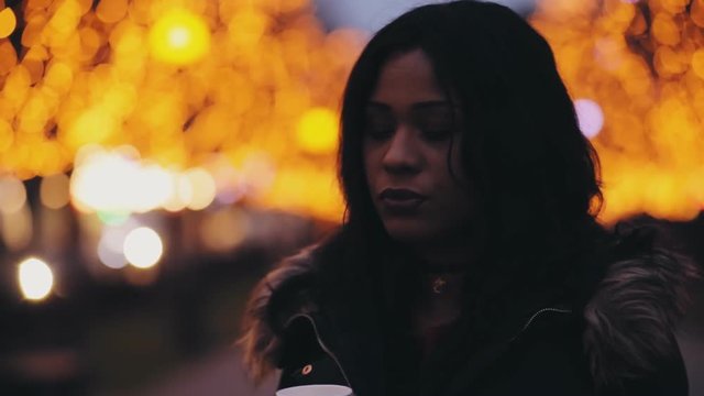 Beautiful multiracial woman drinking tea in night city