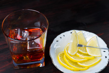 A glass of alcohol and sliced lemon.