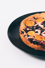 Pie with tangerines and currants on a white table