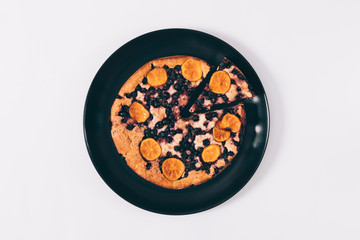 Top view of a cut pie with mandarins and currants