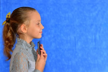 Woman talking by smart phone against blue background.Woman using smart phone,girl writing message,curly hair,pretty face,attractive girl with cell phone,natural make up,woman in white shirt,red lips