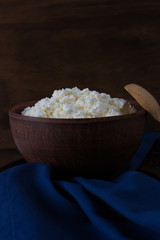 Fresh homemade cottage cheese in clay bowl on blue cloth - healthy breakfast
