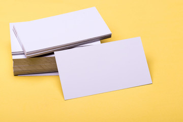 Business cards stack on yellow background. Name cards in white