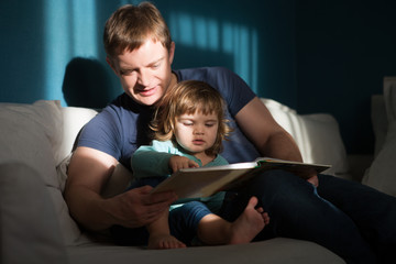 Father reading a story to his child. happy family time together at home.

