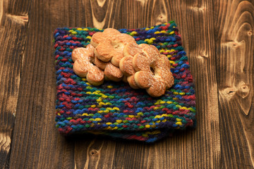Flower shaped biscuits lying on colorful knitted scarf