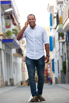 portrait of man walking on street talking on mobile phone