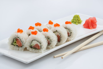 sushi or rolls on a long plate, wooden sticks, red ginger and wasabi